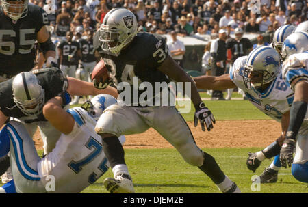 Oakland Raiders Runningback LAMONT JORDAN #34 durchzieht die Verteidigungslinie während Falcons Linebacker ANTHONY Kanone #52 während ihres Spiels im McAfee Coliseum festhält. Stockfoto