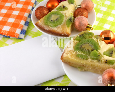Kiwi Kuchen auf Teller mit weißen leeres Papier und Weihnachten Kugeln set Stockfoto