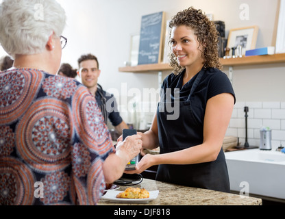 Frau zahlen durch Smartphone im Cafe Stockfoto