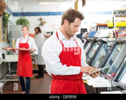 Zuversichtlich männlichen Metzger stehend Arme verschränkt im Store Stockfoto