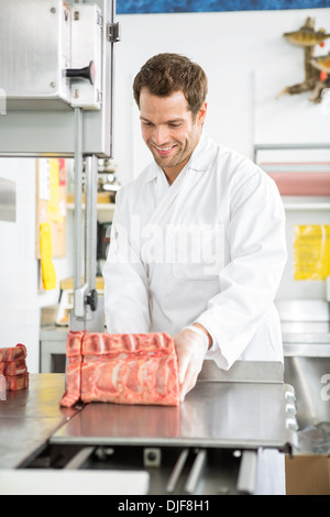 Metzger schneiden Fleisch auf Bandsäge In Shop Stockfoto