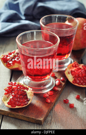 Reife Granatapfel-Frucht und ein Glas Saft auf hölzernen Hintergrund Stockfoto