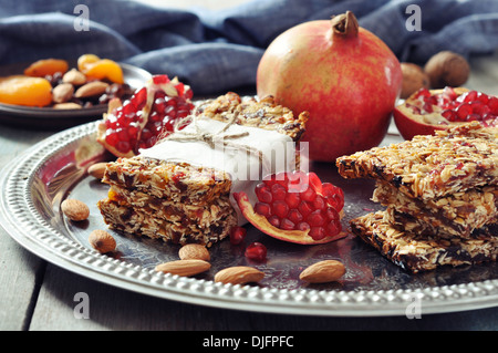 Müsliriegel mit Nüssen, Granatapfel und getrocknete Früchte auf hölzernen Hintergrund auf Teller Stockfoto