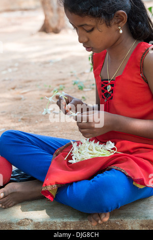 Indische Mädchen saß, eine Kette aus indischen Kork Baum Blumen. Andhra Pradesh, Indien Stockfoto