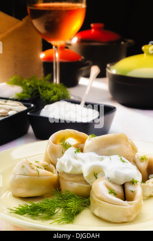 Russische Teigtaschen (Pelmeni) mit saurer Sahne (Smetana) und Fenchel, auf einen reichen Tisch Stockfoto