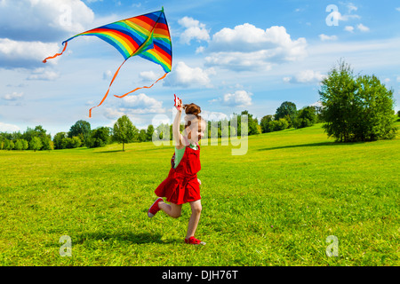 Niedliche kleine Mädchen mit langen Haaren auf sonnigen Sommertag mit Drachen im Feld ausgeführt Stockfoto