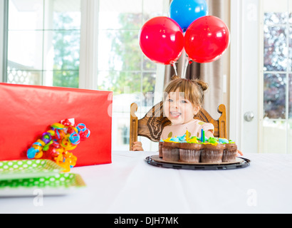 Geburtstagskind mit Kuchen und Gegenwart auf Tisch Stockfoto