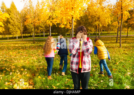 Kinder spielen verstecken und suchen mit jungen zählen und Freunde auf der Flucht Stockfoto