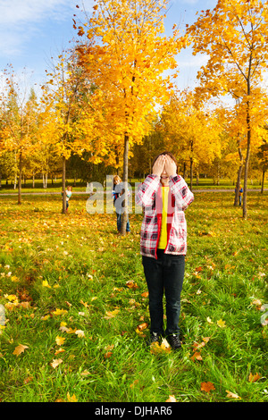 Kinder spielen verstecken und suchen mit jungen zählen Verkleidung Gesicht mit Palmen während andere versteckt sich hinter Herbst männlichen Bäumen Stockfoto