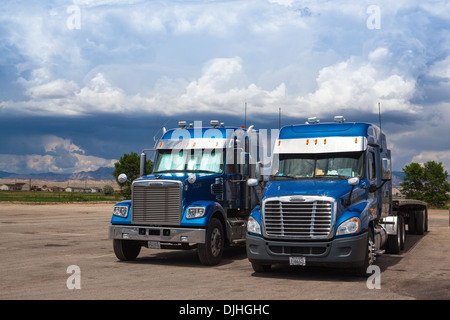 Zwei typische amerikanische blau Freightliner Trucks auf einem Parkplatz vor schweren Sturm in Utah Stockfoto