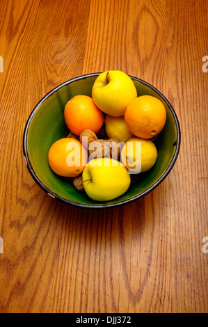 Einige französische Winter Obst, Apfel, Orange, Nüssen, Zitronensaft in einer grünen Schale auf Holztisch Stockfoto