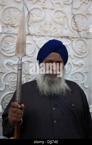 Ein Sikh hält Ordnung am Eingang des Gurdwara Sis Ganj Tempel. Stockfoto