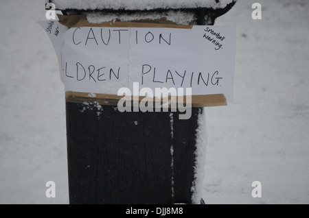 Ein Mülleimer im Schnee mit Schild mit der Aufschrift Vorsicht spielende Kinder Stockfoto