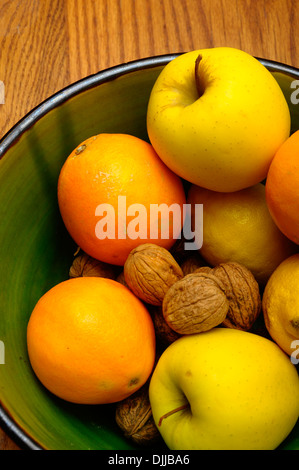 Einige französische Winter Obst, Apfel, Orange, Nüssen, Zitronensaft in einer grünen Schale auf Holztisch Stockfoto