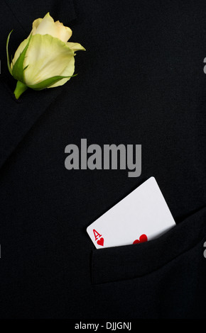 Die Herz-Ass Spielkarte in der oberen Tasche von einer schwarzen Jacke mit einer gelben rose Knopfloch Stockfoto