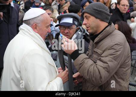 Vatikan, Rom, Italien. 27. November 2013. Papst Francis, während einem wirklich kalten Tag in St. Peter Square, ändern seinen Schal mit einer Kranken Person und seine Helfer in der Generalaudienz vom 27. November 2013 Credit: wirklich Easy Star/Alamy Live News Stockfoto
