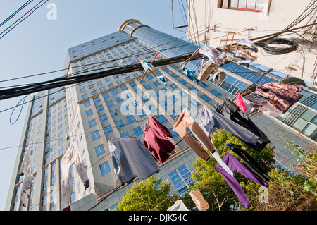 Wäsche auf der Wäscheleine gesehen vom Innenhof mit modernen Gebäude auf Hintergrund in Shanghai, China Stockfoto