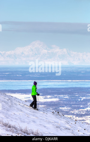 Frau Schneeschuhwandern am Blueberry Hill im Bereich Glen Alpen des Chugach State Park mit Mt. Mckinley (Denali) im Hintergrund Stockfoto