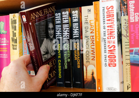 Eine Hand picking The Diary of Anne Frank von einem Bücherregal Stockfoto