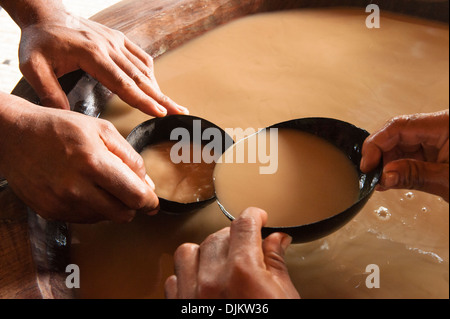 Nahaufnahme von Menschenhänden füllen eine Bilo (Kokosnussschalen als Trinkbecher verwendet) mit Kava aus der großen Hotelkettenhotel (Kava-Schüssel) Fidschi Stockfoto