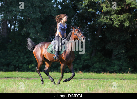 Fröhliches Mädchen und ihr galoppierenden Pferd Stockfoto