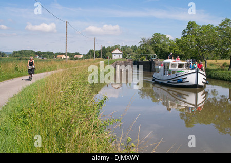 Weibliche Radfahrer fährt mit Leinpfad während Segel für nichtgewerbliche Schifffahrt entlang des Canal du Centre gleich hinter Schloss Burgund Ost-Frankreich Stockfoto