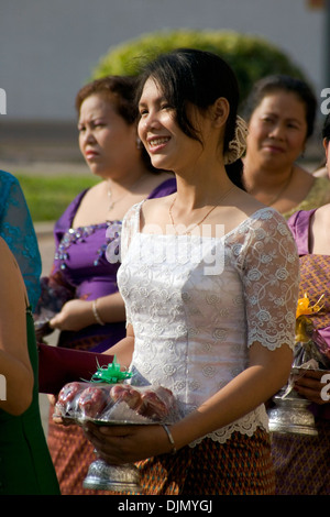 Eine asiatische Frau trägt eine Schale gefüllt mit Äpfeln bei einer traditionellen Hochzeit Zeremonie auf einer Stadtstraße in Battambang, Kambodscha. Stockfoto