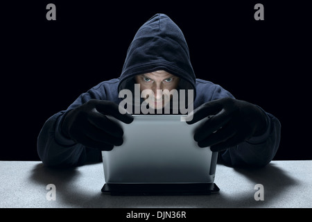 Vermummte männliche Vertreter einer Cyber-kriminellen, mit einem Tabletcomputer. Stockfoto