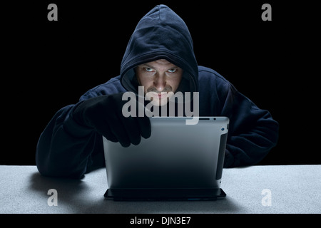 Eine vermummte Mann mit einem Tabletcomputer repräsentieren eine Cyber-kriminellen. Stockfoto