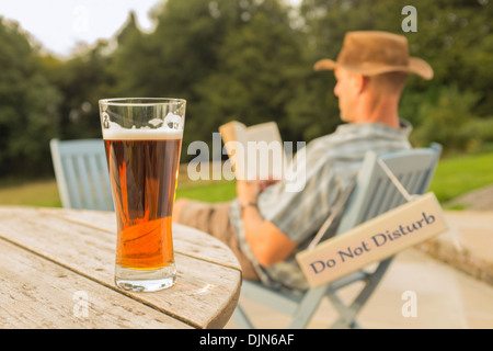 Ein Mann mit einem Buch und Glas Bier entspannen. Stockfoto