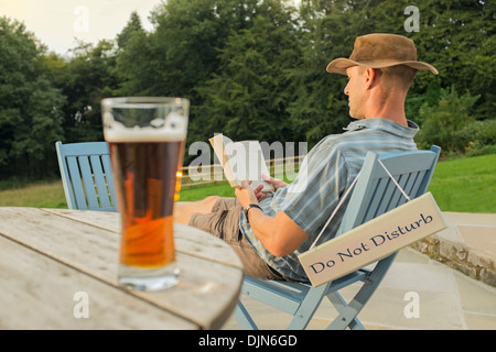 Ein Mann mit einem Buch und Glas Bier entspannen. Stockfoto