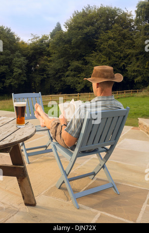 Ein Mann mit einem Buch und Glas Bier entspannen. Stockfoto