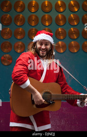 Liverpool, Merseyside, UK, 29. November 2013. Weihnachtsmann busker Robert Bethea, 32 aus Spanien Straßenmusik in Liverpool City Center Holiday Shopping Season, Einzelhandel, Läden, Weihnachtskäufer, Rabatt Verkauf Shopping und Konsum am Schwarzen Freitag als der größte Shopping Tag des Jahres zu sein. Britische Händler haben die US-Post - Urlaub verkauf Bonanza angenommen, obwohl viele Kunden überrascht Links wurden von Wand-zu-Wand Rabatte in Ihre bevorzugten Stores wie einige gingen bonkers für Schnäppchen. Stockfoto