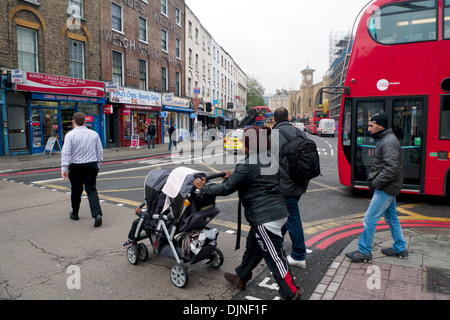 Fußgänger und Mutter, die einen Kinderwagen über eine geschäftige Straße schieben Grays Inn Road mit Bussen Autos Verkehr in King's Cross Gebiet von London, Großbritannien, KATHY DEWITT Stockfoto