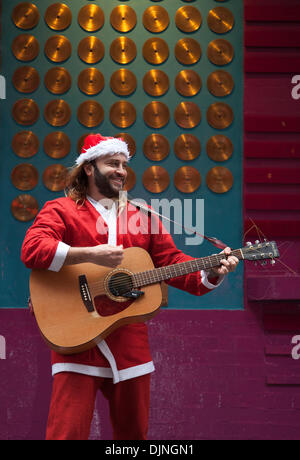 Liverpool, Merseyside, UK, 29. November 2013. Weihnachtsmann busker Robert Bethea, 32 aus Spanien Straßenmusik. Liverpool City Center Holiday Shopping Season, Einzelhandel, Läden, Weihnachtskäufer, Rabatt Verkauf Shopping und Konsum am Schwarzen Freitag als der größte Shopping Tag des Jahres zu sein. Britische Händler haben die US-Post - Urlaub verkauf Bonanza angenommen, obwohl viele Kunden überrascht Links wurden von Wand-zu-Wand Rabatte in Ihre bevorzugten Stores wie einige gingen bonkers für Schnäppchen. Stockfoto