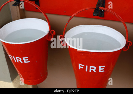 Nahaufnahme von roten Feuer Eimer voller Wasser auf Gleis 1 am Bahnhof Churston, Devon, England. Stockfoto