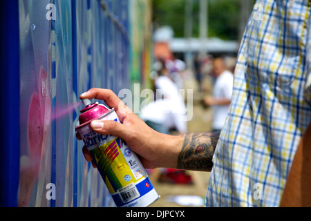 Detail der Hand eines Künstlers mit roten Spray, um das Graffiti an der Wand das Stadion Tor zu malen. Stockfoto