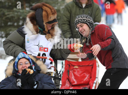 6. März 2010 - Anchorage, Alaska, USA - Nick Manwaring rundet eine Hot-Dog-Übergabe an vorbeikommende Musher KATHLEEN FREDERICK von Willow bei Meile vier wo läuft der Weg neben dem Wesleyan Laufwerk während des Iditarod feierlichen Beginn Samstagmorgen. (Kredit-Bild: © Erik Hill/Anchorage Daily News/ZUMA Press) Stockfoto