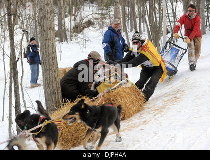 6. März 2010 funktioniert - Anchorage, Alaska, USA - JOHN STEWART von Schottland, um seinen Schlitten und Iditarider FRAN LOCKWOOD von Indiana aus einem Ballen Heu Universität See entlang während des Iditarod feierlichen Beginn Samstag zu extrahieren. (Kredit-Bild: © Erik Hill/Anchorage Daily News/ZUMA Press) Stockfoto