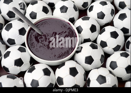 Brasilianischer Kultur auf dem Tisch verfügt über eine Schüssel mit frischen Acai umgeben von Fußball Fußbälle Stockfoto