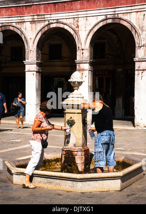 Paar füllen Flaschen mit Wasser aus öffentlichen Brunnen, Venedig, Veneto, Italien Stockfoto