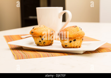 Zwei Vanille Muffins mit Schokoladenstückchen mit einer Tasse Kaffee Stockfoto