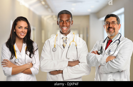 Gruppe von drei verschiedenen Ärzten mit Armen gekreuzt im Gebäude des Krankenhauses Stockfoto