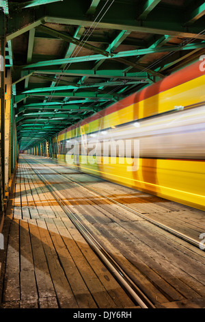 Abstrakte Straßenbahn Lichtspur im unteren Teil des Stahlbinders Gdanski Brücke in Warschau, Polen, Fluchtpunktperspektive. Stockfoto