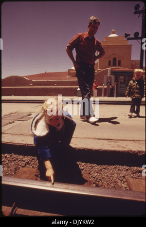 EIN KIND STELLT PFENNIGE AUF DER STRECKE AN DER ALBUQUERQUE, NEW MEXICO, BAHNHOF UND WARTET AUF DEN SÜDWESTEN... 555990 Stockfoto