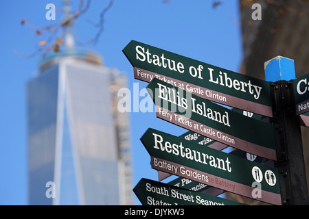 Richtung unterzeichnet, die Freiheitsstatue und Ellis Island mit einem Trade Center (WTC 1) im Hintergrund, New York. Amerika Stockfoto