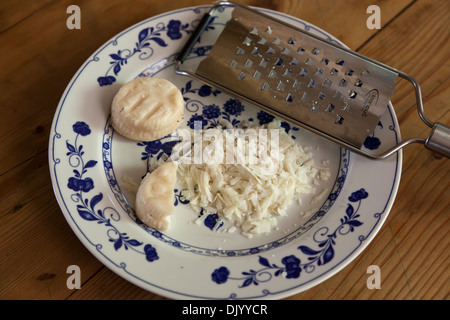 Schafskäse grob vom Handheld Reibeisen gerieben. Stockfoto