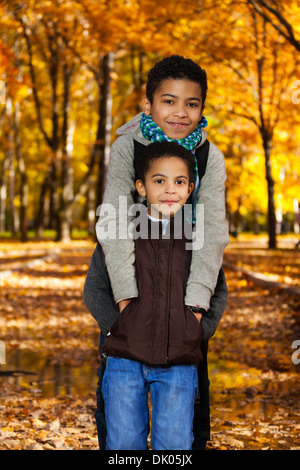 Zwei glückliche 8 und 10 jungen schwarzen Brüder stehen im Herbst orange park Stockfoto