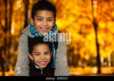 Enge Porträt zweier glücklich 8 und 10 jungen schwarzen Brüder stehen im Herbst orange park Stockfoto