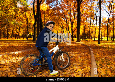 Glücklich lächelnd 8 Jahre schwarzer Junge mit dem Fahrrad in den Herbst Park gelehnt auf dem Fahrrad Heck Stockfoto